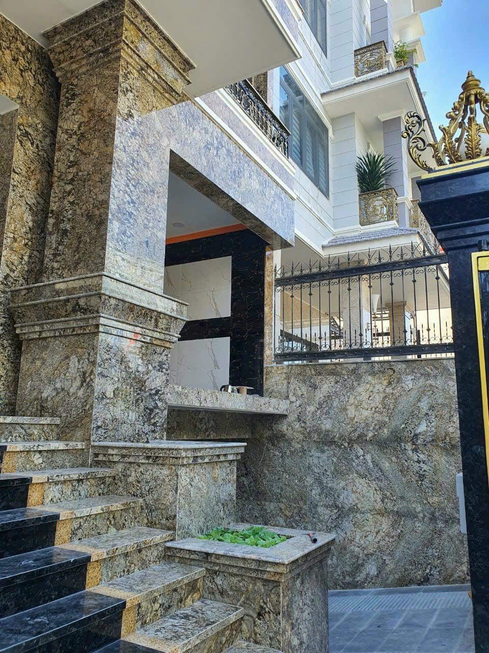Mặt tiền một ngôi nhà sang trọng ốp đá hoa cương màu nâu trầm với những đường vân đá độc đáo, thể hiện sự bề thế và đẳng cấp.